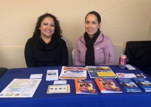 Two DCSS employees sitting behind a table with a blue tablecloth and brochures